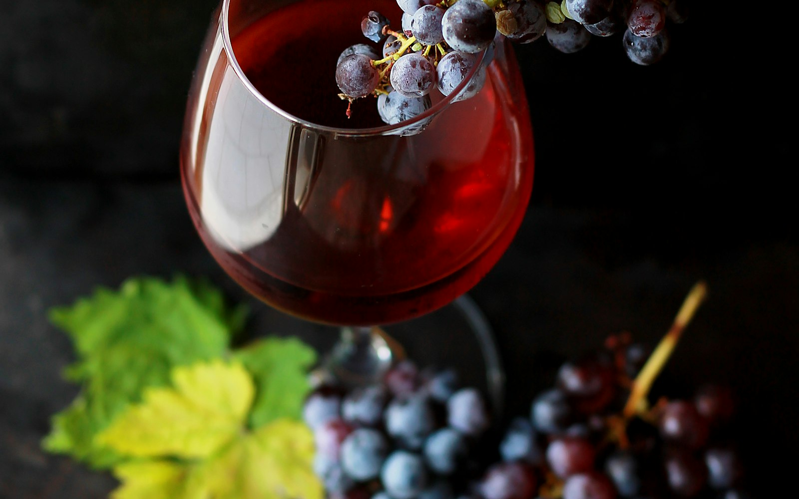 Red grapes resting against a glass of wine